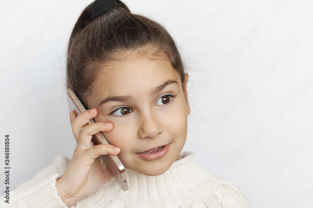 Portrait of a smiling cute child girl holding smartphone over white background. Happy child face. Technology Portrait of a smiling cute child girl holding smartphone over white background. Happy child face. Technology