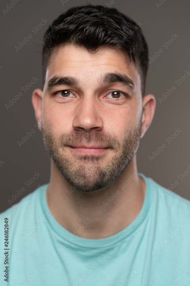 Handsome caucasian white male with black short hair and stubble with light blue t shirt Handsome caucasian white male with black short hair and stubble with light blue t shirt