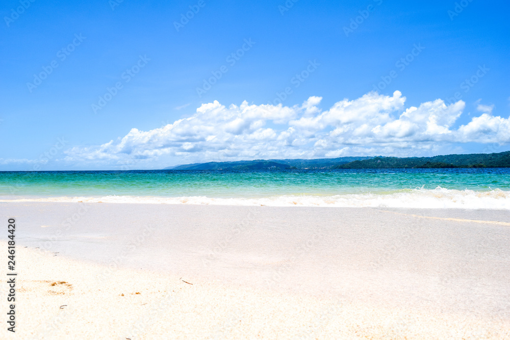 Caribbean island white beach with blue turquoise ocean and waves, blue sky with some clouds, paradise island at cayo levantado