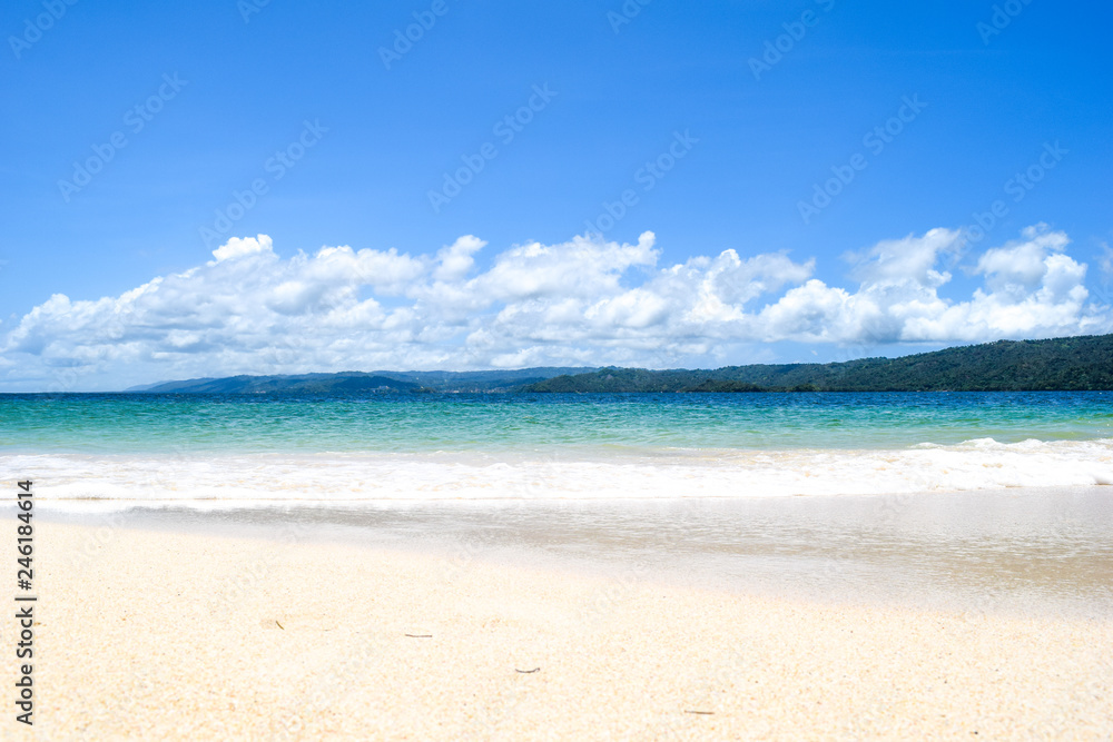 island with white beach blue turquoise ocean and waves, blue sky with some clouds, paradise island at cayo levantado