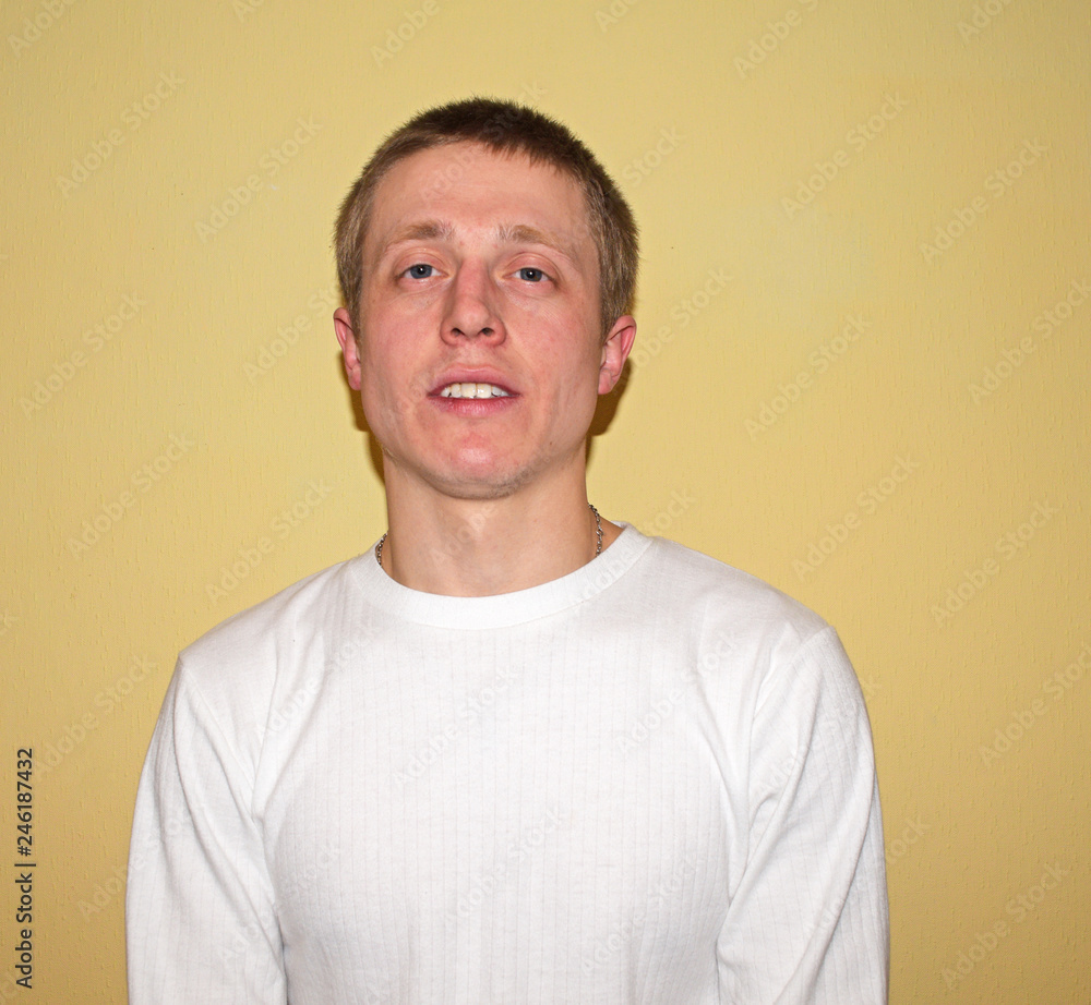 Portrait of a young thin man in a white jacket against a yellow wall. Portrait of a young thin man in a white jacket against a yellow wall.