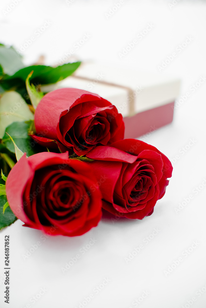 Fototapeta premium Flowers composition with gift box heart shaped made of rose flowers on white background. Flat lay, top view, copy space