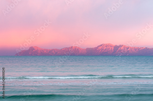 Rosaroter Himmel über den Bergen am Horizont beim Sonnenuntergang am Meer