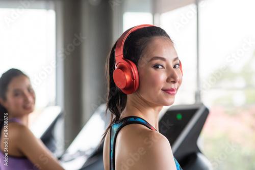 Young asian woman listening music with headphones in the gym.