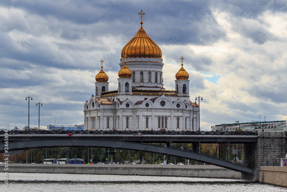 Cathedral of Christ the Saviour in Moscow on a background of Bolshoy Kamennyi Bridge in cloudy autumn day against dramatic sky