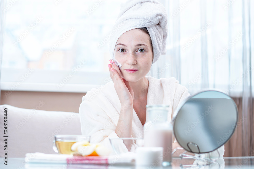 Beautiful young woman applying cream of natural cosmetics on face moisturizing the skin. Hygiene and care for the skin Beautiful young woman applying cream of natural cosmetics on face moisturizing the skin. Hygiene and care for the skin