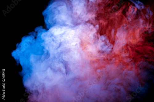A jet of smoke soaring and exhaled from a vape evaporates in the neon light of a pink blue violet color against a dark background.