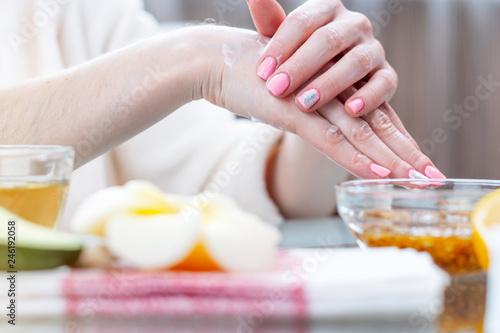 Woman applying the cream on her hands nourishing them with natural cosmetics close-up. Hygiene and care for the skin