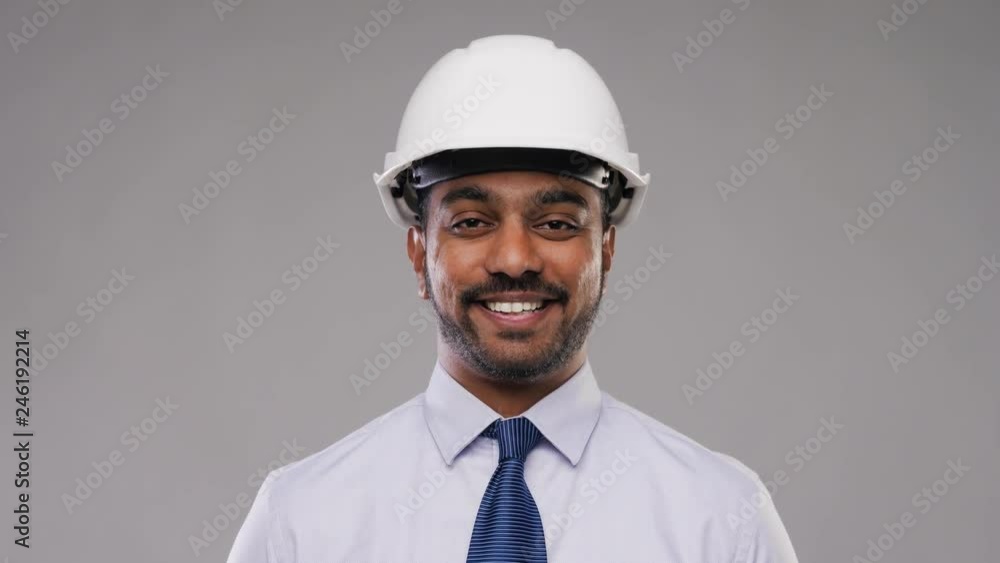 architecture, construction business and building - smiling indian architect or businessman in helmet over grey background architecture, construction business and building - smiling indian architect or businessman in helmet over grey background