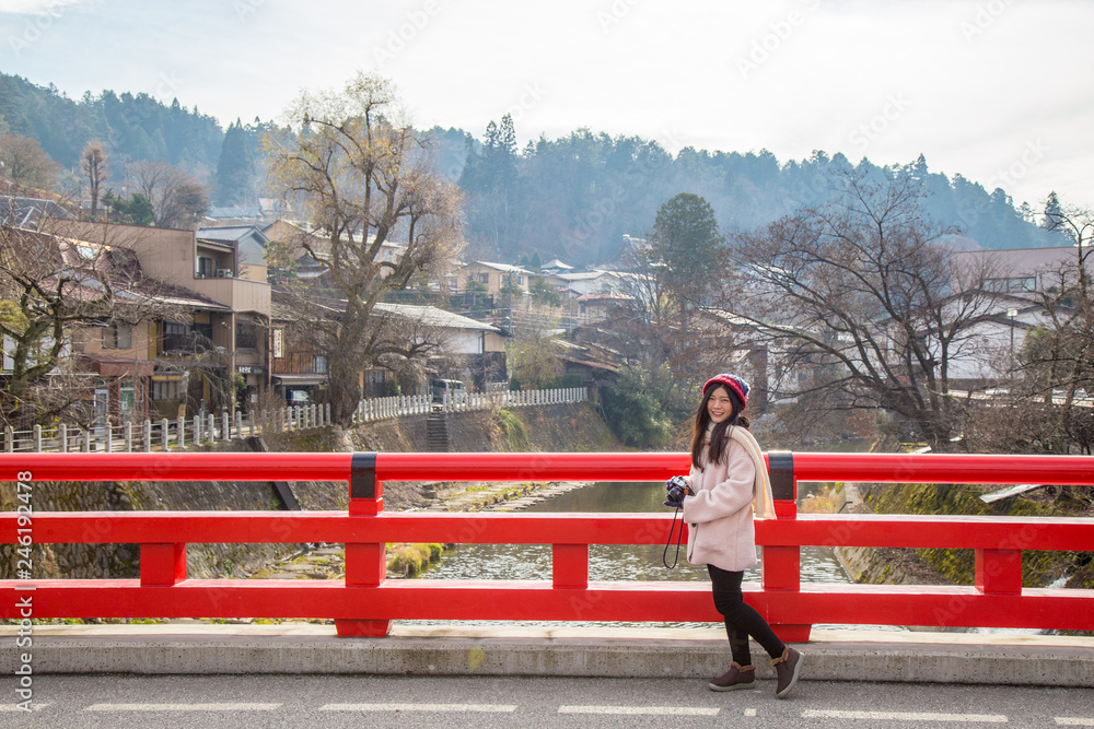 Asian cute girl on Nakabashi Bridge with red colour is one of the symbols of Hida-Takayama old town in Chubu region, Japan Asian cute girl on Nakabashi Bridge with red colour is one of the symbols of Hida-Takayama old town in Chubu region, Japan