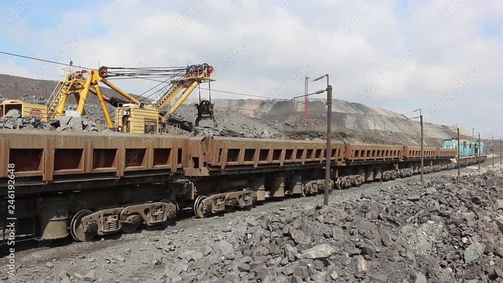Excavator loads iron ore into a freight train Excavator loads iron ore into a freight train
