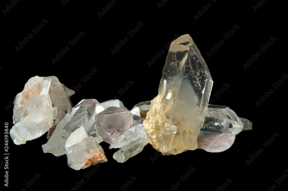 Numerous large clear quartz crystal points on black background, surface level and up close on black background.