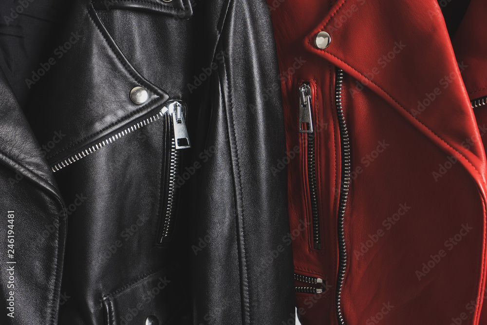 Red and black leather jackets with metallic zipper and buttons. Man and woman concept. Detailed closeup view. Red and black leather jackets with metallic zipper and buttons. Man and woman concept. Detailed closeup view.