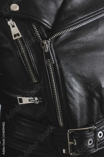 Black leather jackets with metallic zipper and buttons. Classic clothes for biker. Detailed vertical closeup view.