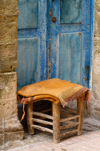 Kleiner Hocker vor blauer Tür in der Medina von Essaouira, Marokko.