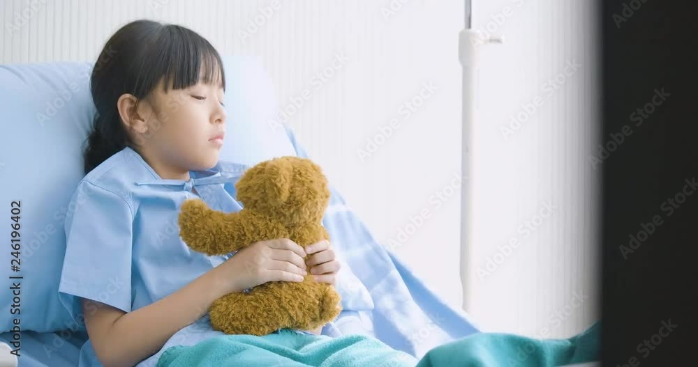 Little asian girl lying alone in hospital and hugging toy, unhappy child missing parents, illness and treatment. Little asian girl lying alone in hospital and hugging toy, unhappy child missing parents, illness and treatment.