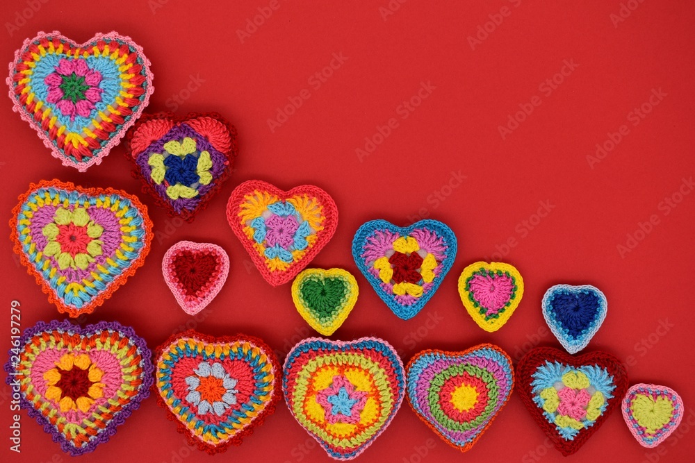 Knitted hearts on a red background. Handmade, amigurumi hobby, love, Valentine's Day, decoration, design.