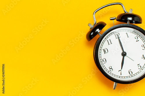 Black retro alarm clock on yellow background top view Flat lay copy space. Minimalistic background, concept of time, deadline, time to work, morning