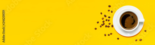 Flat lay cup of black coffee and coffee beans on yellow background top view copy space. Minimalistic food concept, morning breakfast, time to work, hot drink, coffee background