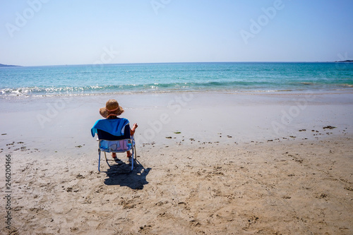 Mulher sentada a aproveitar banhos de sol nas suas férias de praia em Espanha photo