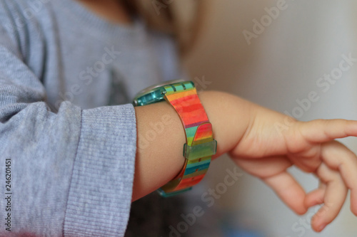 Baby girl carefully looking at colorful smart wrist watches at home.