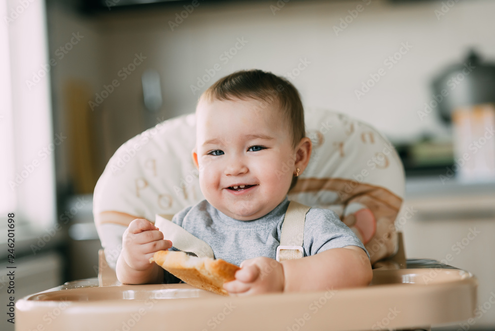 baby in the kitchen in the high chair there is a piece of bread baby in the kitchen in the high chair there is a piece of bread
