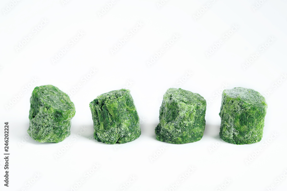 Frozen spinach on a white background. Spinach has the shape of cylindrical bars. Bars are displayed in a row. Close-up. Frozen spinach on a white background. Spinach has the shape of cylindrical bars. Bars are displayed in a row. Close-up.