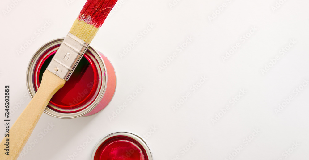 Paintbrush on red paint pot on white table top view