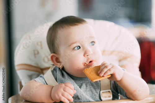 little girl in a high chair eating cookies