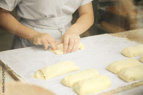 Professional chef rolling dough in the kitchen. Commercial bakery.