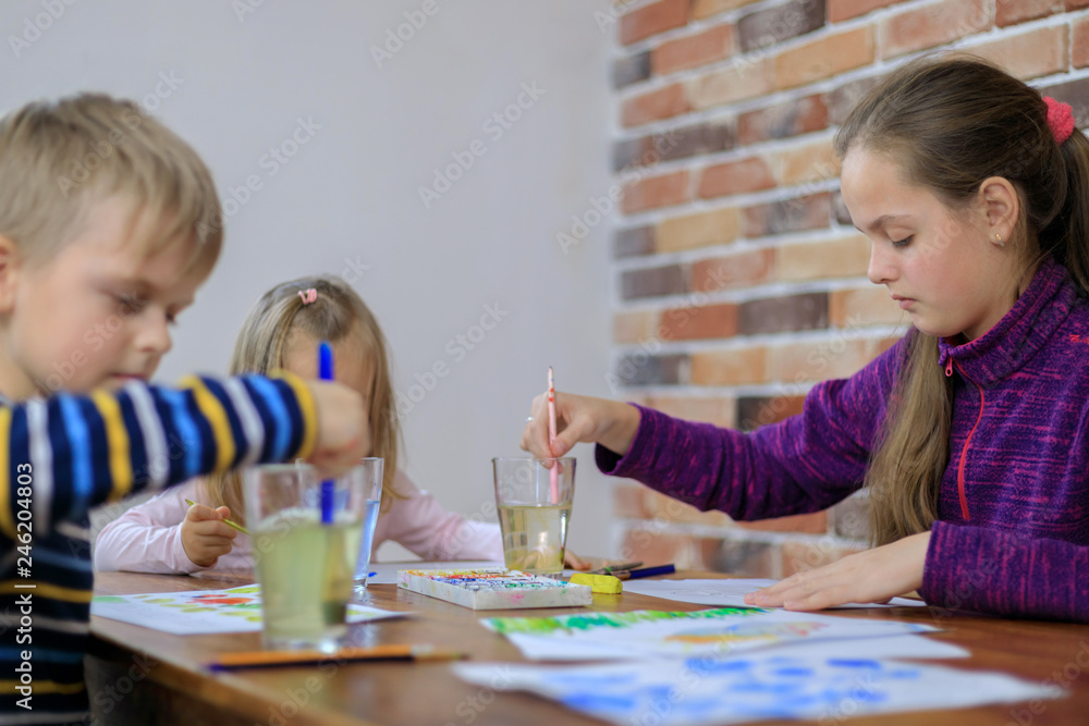 Fototapeta premium Happy children - boy and two girls is drawing with colorful paint
