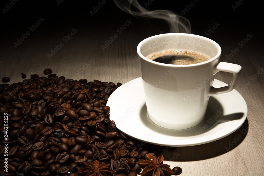 Fototapeta premium coffee still life from a cup of coffee, beans and cinnamon sticks on a black background