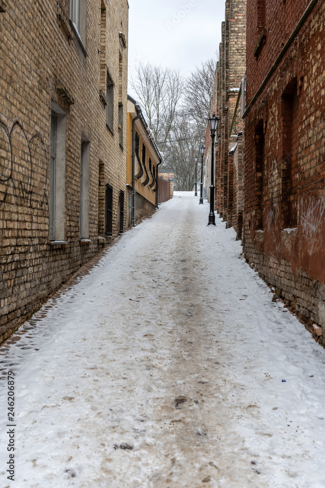Riga. Latvia. Winter landscape with pedestrian path between old brick houses.