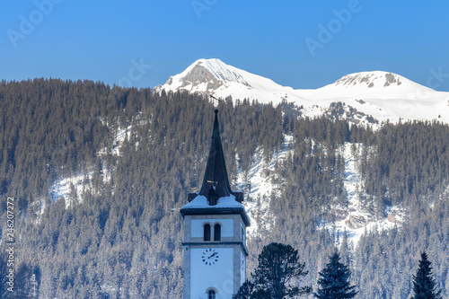 Kirchturmspitze vor einem Berg