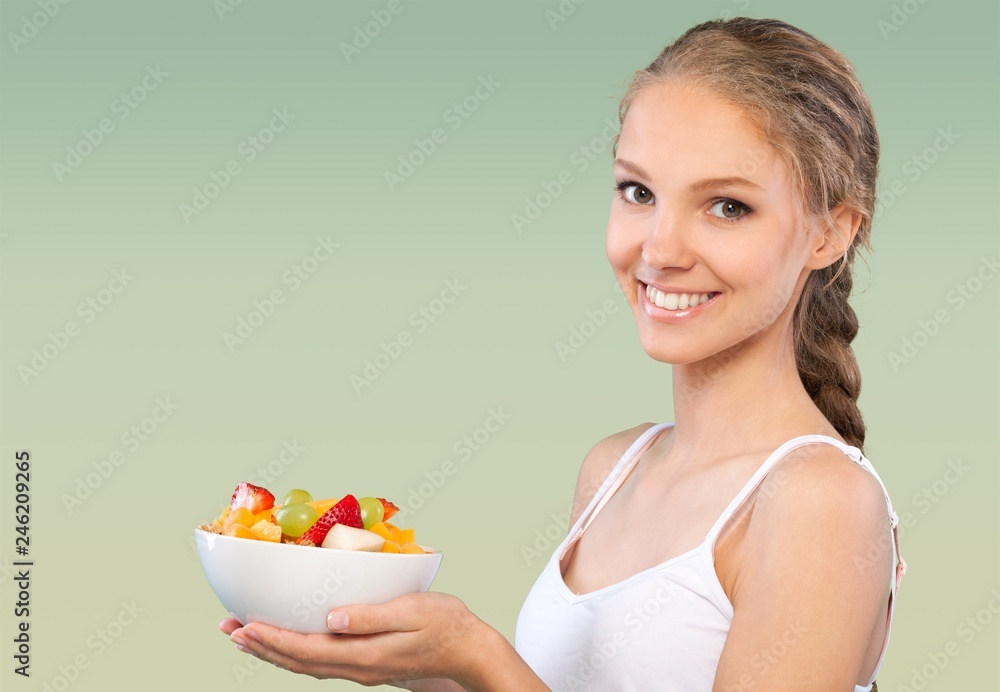Young woman eating delicious food with fork on green background Young woman eating delicious food with fork on green background