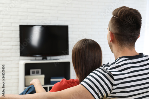 Couple watching TV together in living room. Space for text