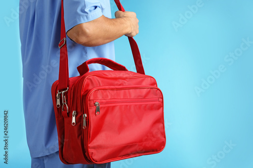 Male doctor with first aid kit and space for text on color background, closeup. Medical object