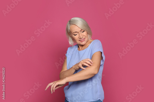 Fototapeta Naklejka Na Ścianę i Meble -  Mature woman scratching arm on color background. Annoying itch