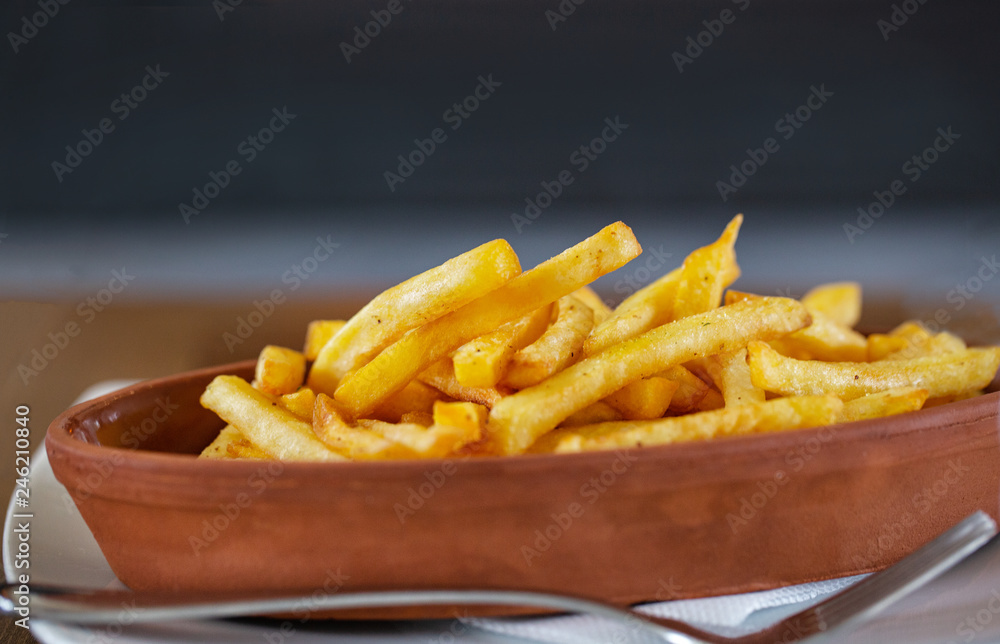 Clay oval plate of french fries on a wooden table Clay oval plate of french fries on a wooden table
