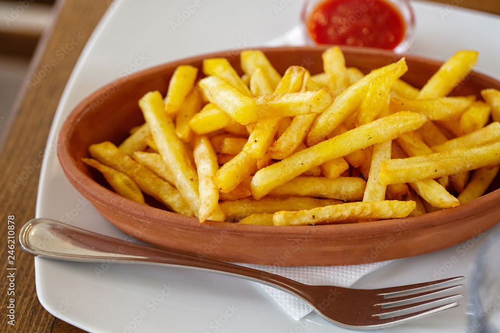 Clay oval plate of french fries on a wooden table Clay oval plate of french fries on a wooden table