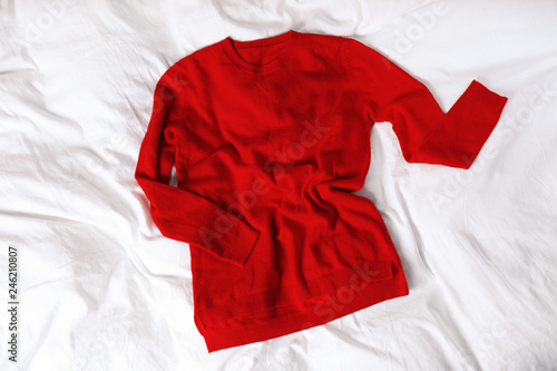 Red cashmere sweater on white fabric, top view