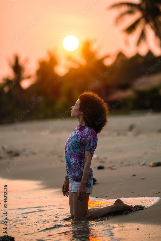Mixed race woman on a tropical beach during amazing sunset.