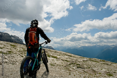 man with an electric bike, e-bike, ebike, mtb, observes Cima Grostè Peak, Dolomite mountains, unesco heritage, Madonna di Campiglio, summer, sport, adventure, travel, Alps, Trentino, Alto Adige, Italy