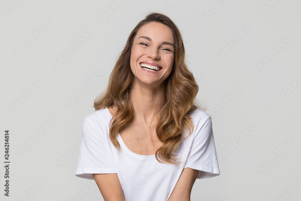 Happy cheerful young woman with beautiful face, teeth and hair laughing looking at camera on white light background, smiling pretty girl model having fun isolated on blank grey studio wall, portrait Happy cheerful young woman with beautiful face, teeth and hair laughing looking at camera on white light background, smiling pretty girl model having fun isolated on blank grey studio wall, portrait