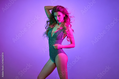 High Fashion. Gorgeous Disco Party girl with glowing makeup, purple hair. Young beautiful model woman in Colorful neon Light. Night Clubbing. Stylish fashionable portrait, make up
