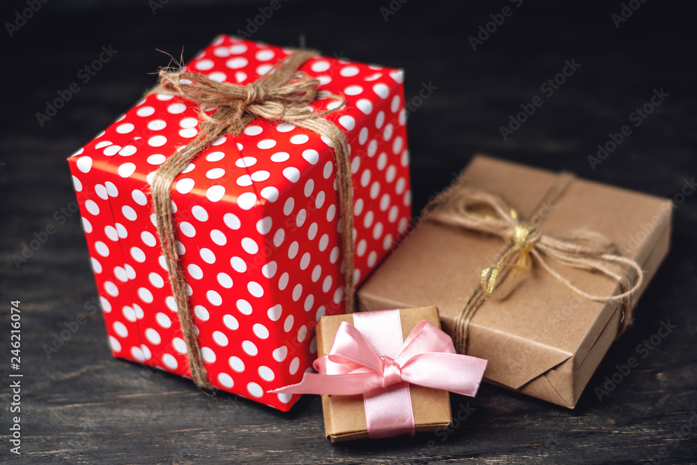 Holiday gift boxes Packed in crafting paper and red polka dots on dark wooden background. Concept of cards with gifts Holiday gift boxes Packed in crafting paper and red polka dots on dark wooden background. Concept of cards with gifts