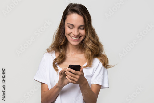 Happy teen girl using smartphone chatting in social media, smiling young woman user holding cellphone texting in messenger on phone, shopping in mobile app isolated on white blank studio background