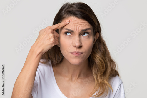 Dissatisfied stressed depressed young woman touch forehead worried about skin wrinkle isolated on studio background, cosmetology botox injection anti aging cream concept, cosmetology facial treatment