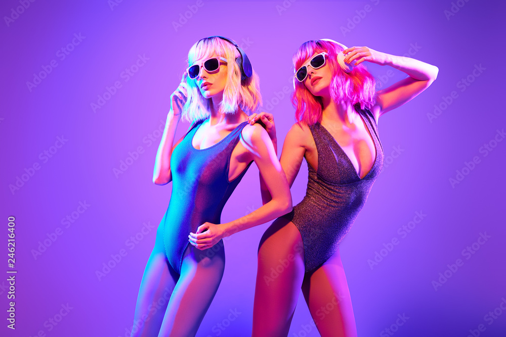 Two sexy fashionable DJ girl in party outfit dance. Colorful neon uv light.  Rave house music vibes. Model woman with Dyed Hair, makeup. High Fashion.  Night Club neon concept. foto de Stock