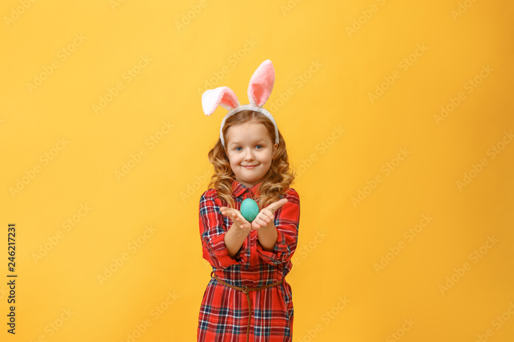 Cheerful little kid girl with bunny ears with an easter egg on a colored background. Cheerful little kid girl with bunny ears with an easter egg on a colored background.